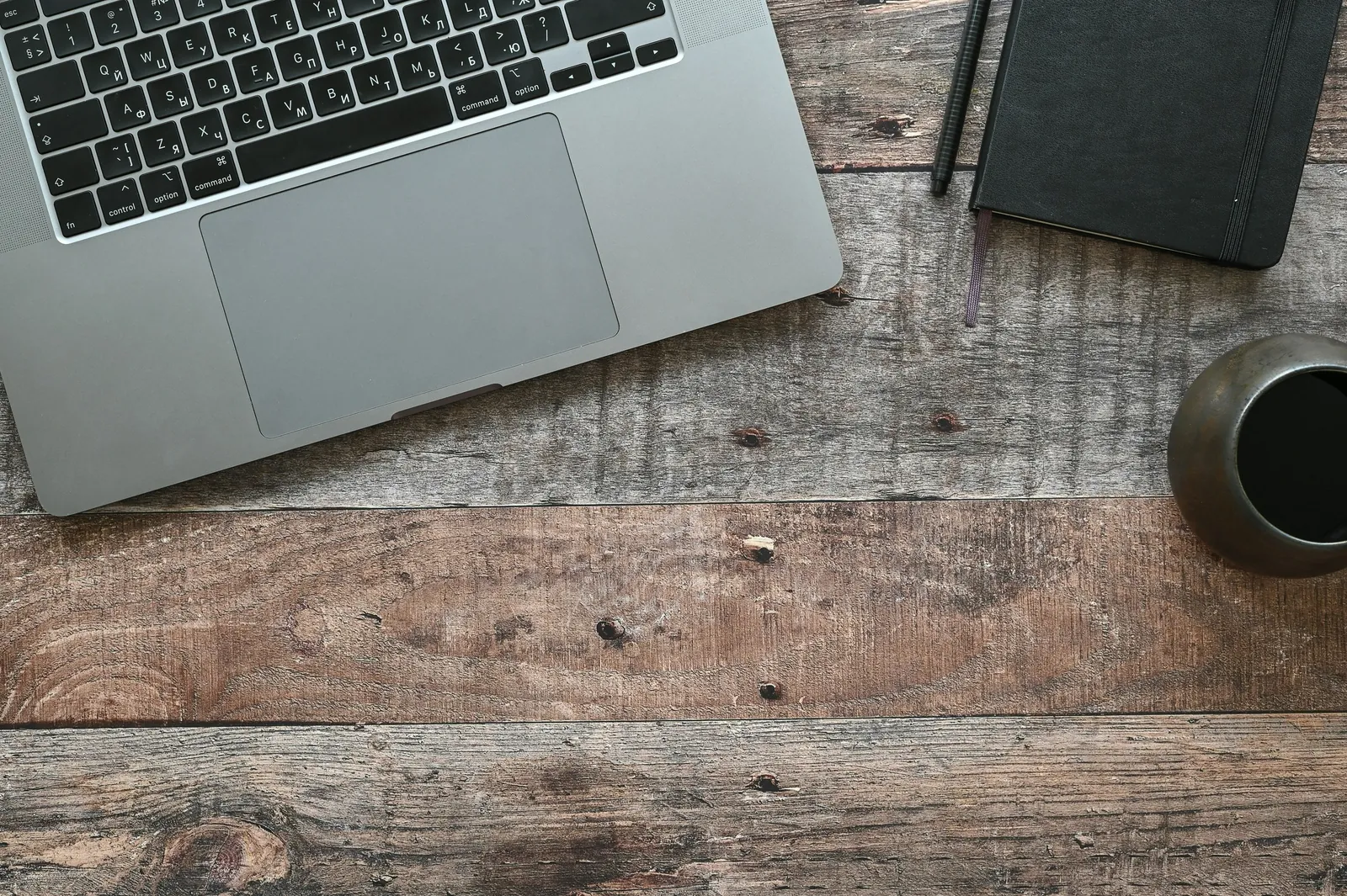 Notatbok, kaffe og laptop på et skrivebord